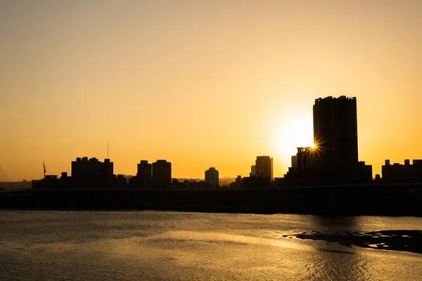 Sylwetka budynków z rzeką o zachodzie słońca — Zdjęcie stockowe