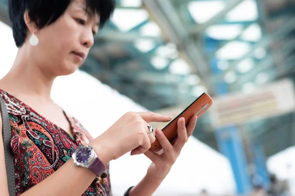 Volwassen reizende vrouw te wachten en het gebruik van een mobiele telefoon — Stockfoto