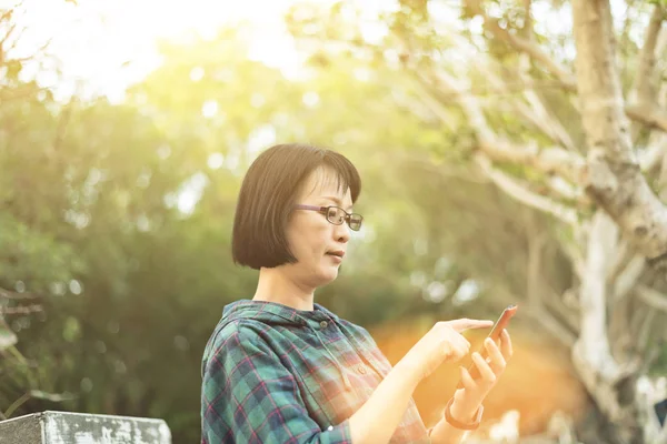 Asiática madura mujer usando celular — Foto de Stock