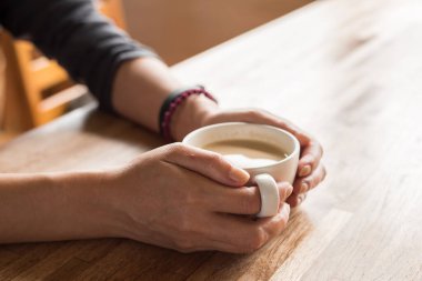 Kadın elinde bir fincan kahve tutuyor.