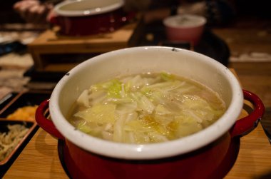 Sebzeli ve domuzlu sıcak tencere yiyen kadının yakın plan görüntüsü.