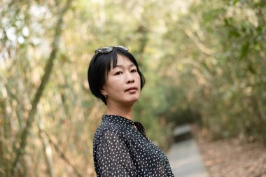 Yetişkin Asyalı kadın portresi geziyor ve açık havada yürüyüş yapıyor.