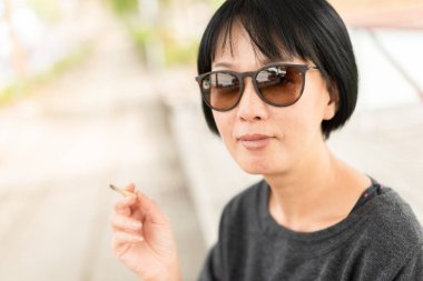 Şehirde sigara içen gözlüklü modern Asyalı güzellik