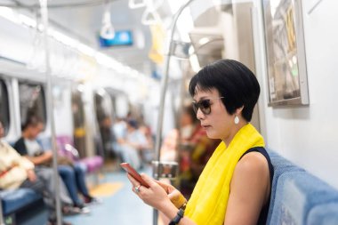 copyspace ile Mrt vagonunda akıllı telefon kullanarak olgun Asyalı kadın