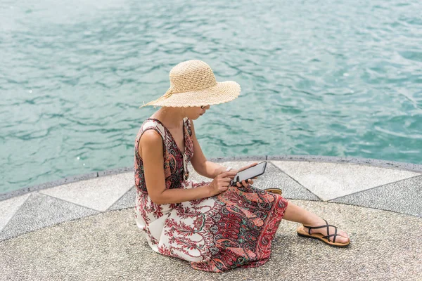 台湾のサンムーン湖で携帯電話を使って桟橋に座って帽子をかぶったアジアの女性 — ストック写真