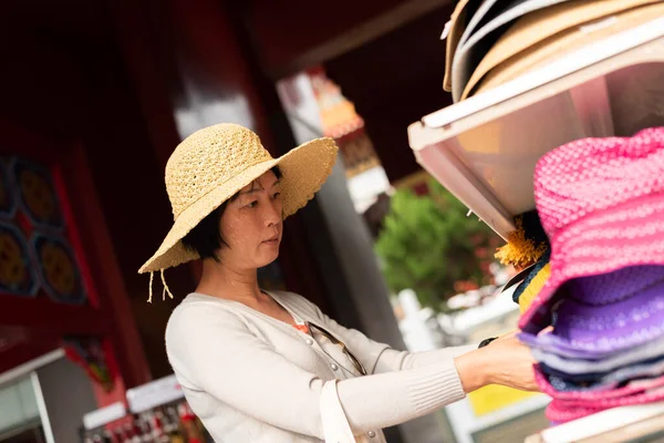 旅行妇女在商店购物和采摘帽子 — 图库照片