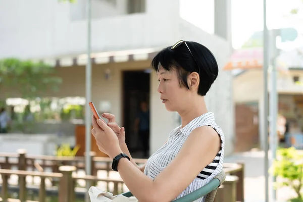 Vrouw Zitten Het Gebruik Van Mobiele Telefoon Buitenlucht — Stockfoto