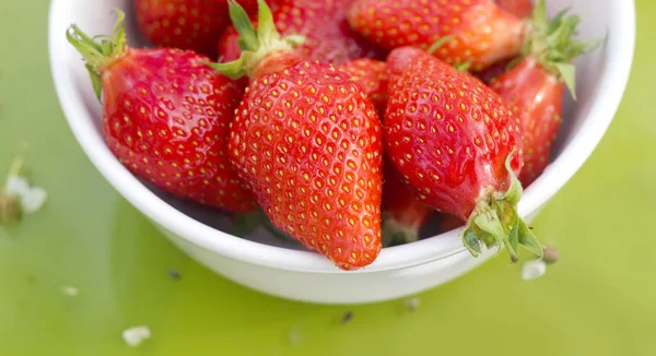 Srawberries in white bowl on green — Stock Photo, Image