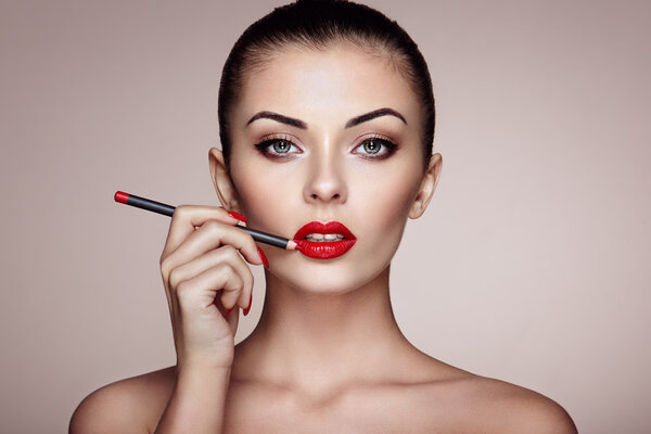 Beautiful woman paints lips with lipstick