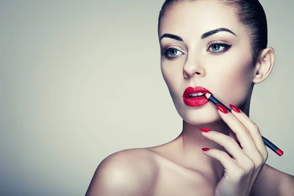 Beautiful woman paints lips with lipstick — Stock Photo, Image