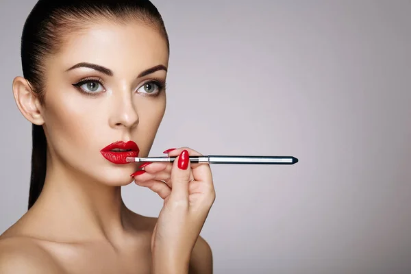 Beautiful woman paints lips with lipstick — Stock Photo, Image