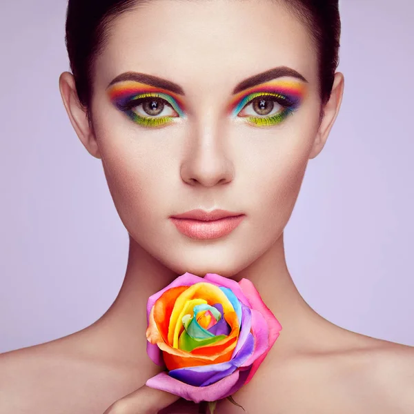 Porträt einer schönen jungen Frau mit Regenbogenrose — Stockfoto