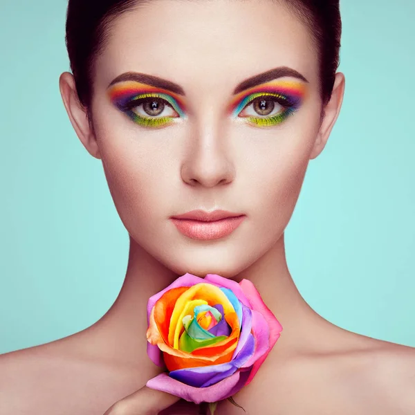 Portret van mooie jonge vrouw met regenboog roos — Stockfoto