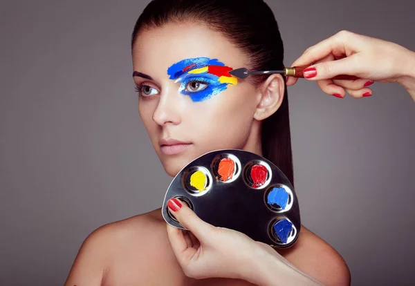 Maskenbildnerin trägt buntes Make-up auf — Stockfoto