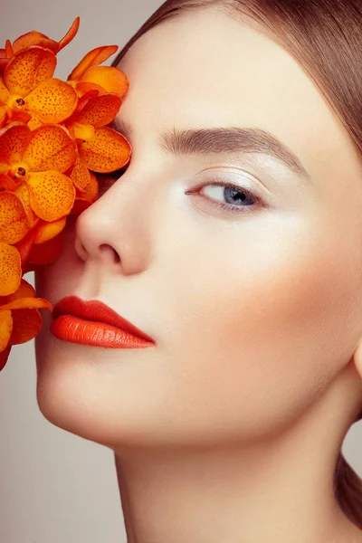 Portrait of beautiful young woman with orchid — Stock Photo, Image