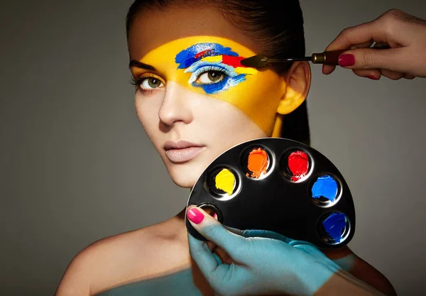Maskenbildnerin trägt buntes Make-up auf — Stockfoto