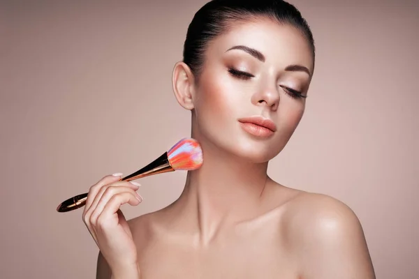 Hermosa mujer aplica tono de piel con cepillo —  Fotos de Stock