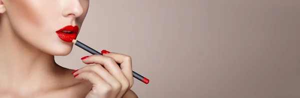 Mooie vrouw schildert lippen met lippenstift — Stockfoto