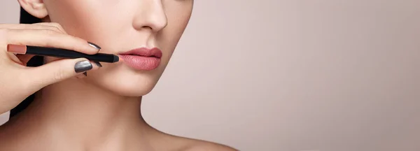 Mooie vrouw schildert lippen met lippenstift — Stockfoto