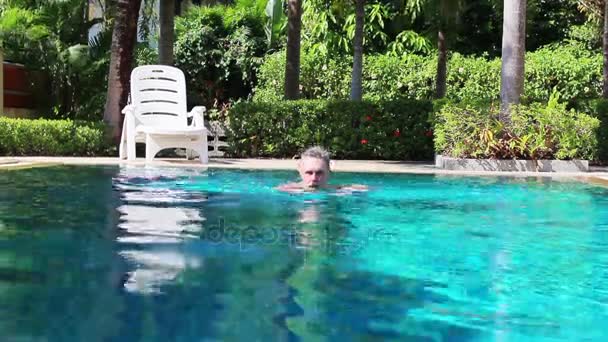 Een oudere man in een zwembad zwemmen — Stockvideo