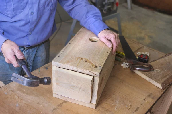 Man inserts the bottom of the birdhouse — Stock Photo, Image