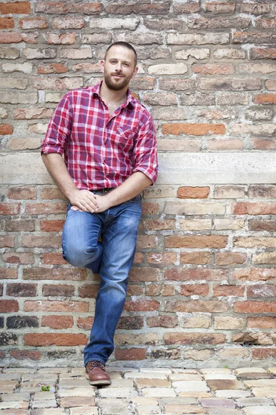 Man standing against brick wall — Stock Photo, Image