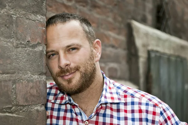 Man met baard versteld op bakstenen muur — Stockfoto