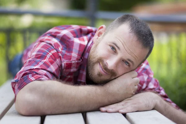 Homme beau barbu couché sur un banc — Photo