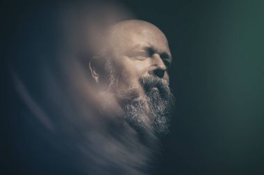 siyah arka plan üzerine sakallı kel adam