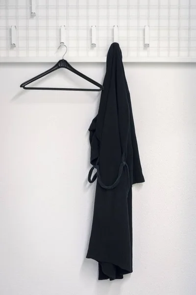 Am Kleiderschrank hängt ein schwarzer Bademantel — Stockfoto