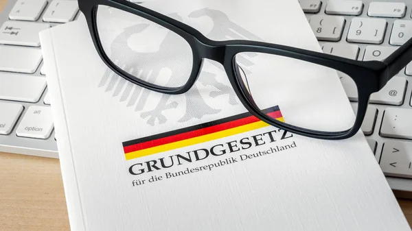 Das deutsche Grundgesetz mit einer Brille auf der Tastatur. — Stockfoto