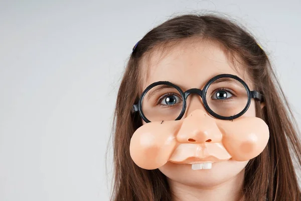 Liten flicka med falska näsa och glasögon — Stockfoto