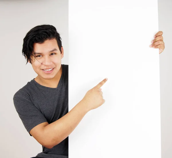 Young latino man pointing at blank sign — Stock Photo, Image