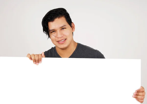 Friendly young latino man holding white sign — Stock Photo, Image