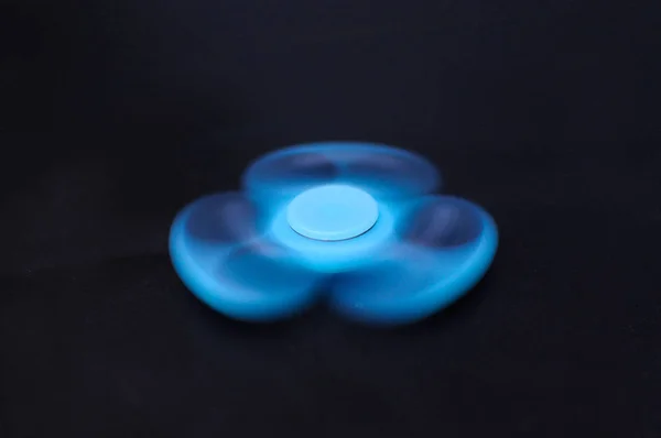 Fidget spinner girando no fundo escuro — Fotografia de Stock