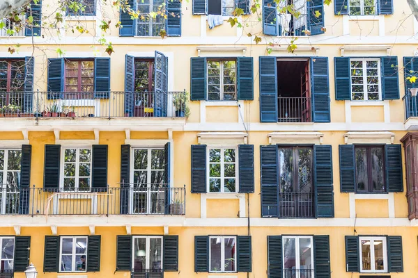 Schwarze Fensterläden auf gelbem Putz — Stockfoto