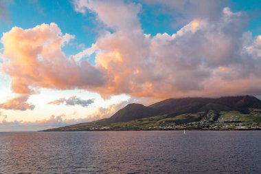 Turuncu bulutlarda mavi gökyüzü üzerinde yeşil ada