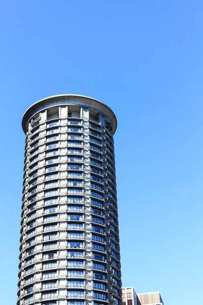 Круглая кондо-башня, взмывающая в голубое небо — стоковое фото