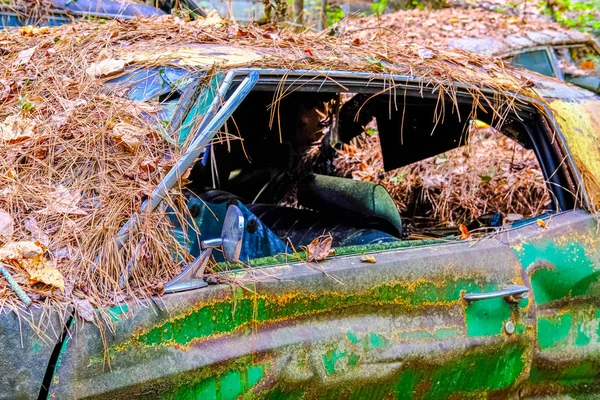 Carro verde destruído coberto com palha — Fotografia de Stock