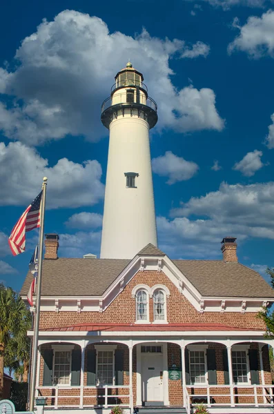 White Lighthouse Behind Brick House with Flag — Stock Photo, Image