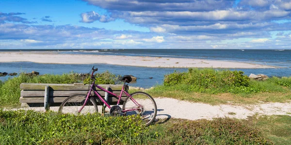 Bicicleta roxa e banco pela praia — Fotografia de Stock