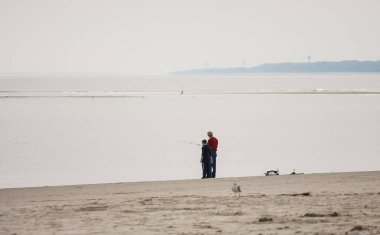 Emekli adam toruna balık tutmayı öğretiyor.