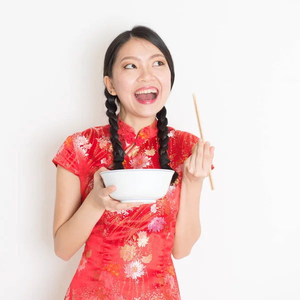 Восточная женщина в красном кипао ест палочками для еды — стоковое фото