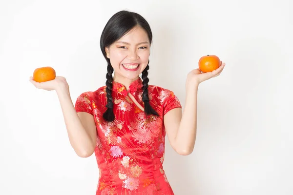 Oriental menina em vermelho qipao segurando mandarina laranja — Fotografia de Stock