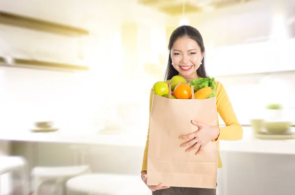 Kvinna med matvaror väska i kök — Stockfoto
