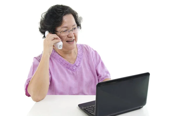 Mulher adulta sênior usando telefone e computador — Fotografia de Stock