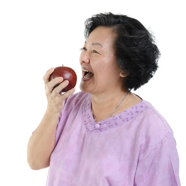 Літня доросла жінка їсть яблуко — стокове фото