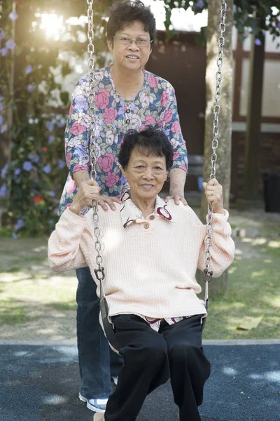 屋外の遊び場でスイングを再生アジアのシニア大人の女性 — ストック写真