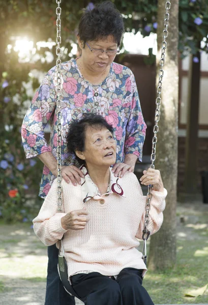 Asiatiska äldre kvinnor spelar swing på lekplatsen utomhus — Stockfoto