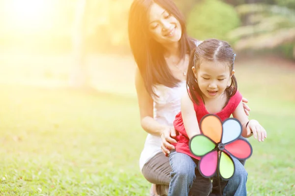 Madre e hija jugando molino de viento en el parque al aire libre . — Foto de Stock